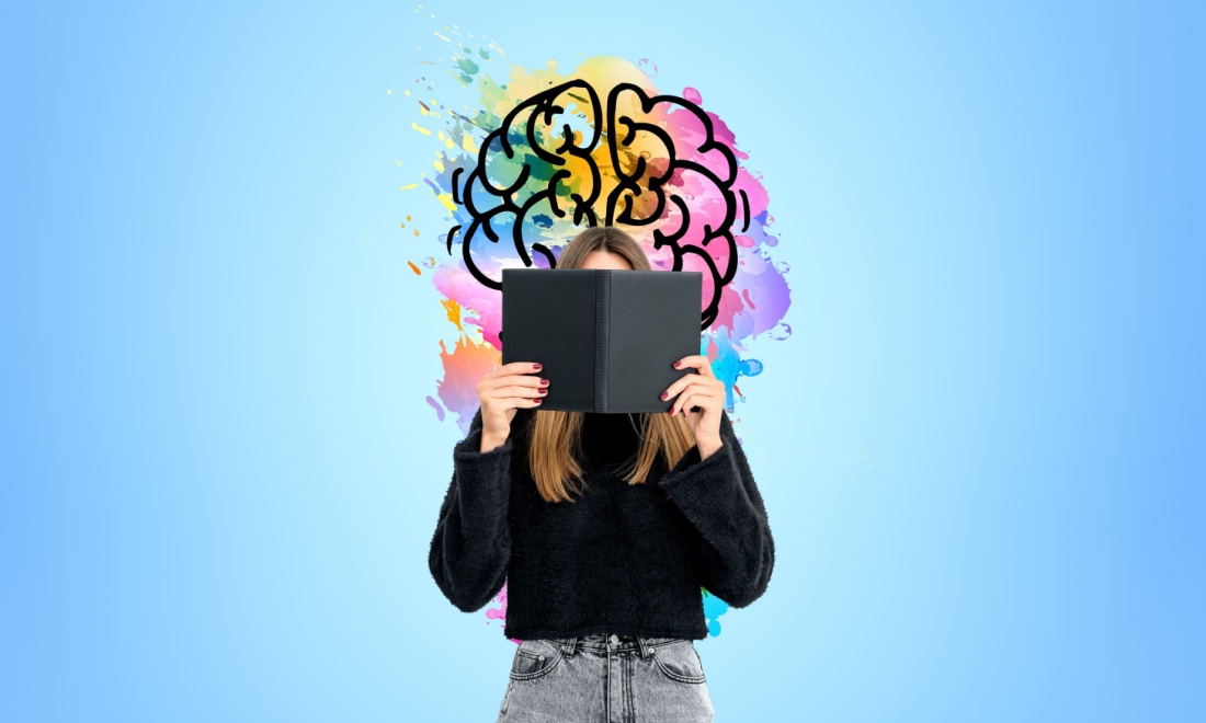 Woman reading a book in front of colourful brain image - Want to keep your brain performing at its peak? Learn a language!  by Regina Coeli