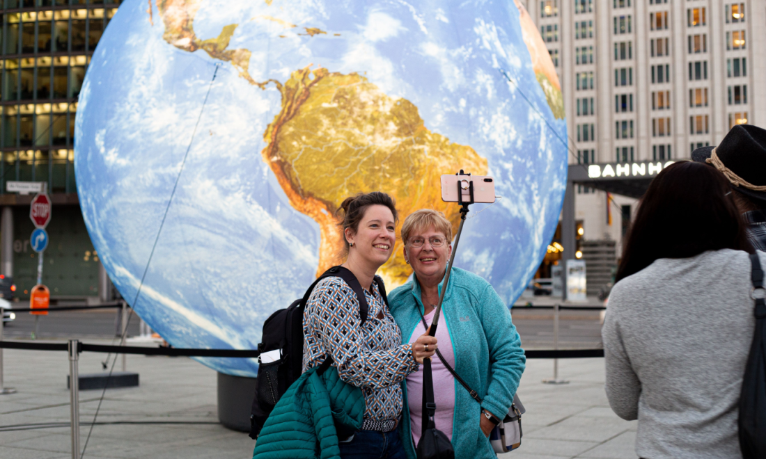 Tourists standing happy in front of a globe in Berlin