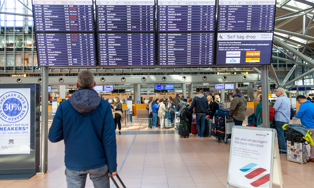 travellers looks at departure boards at hamburg airport