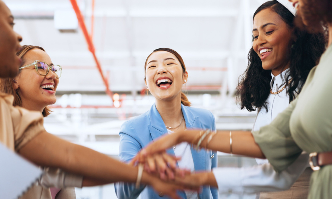 business women joining hands and smiling