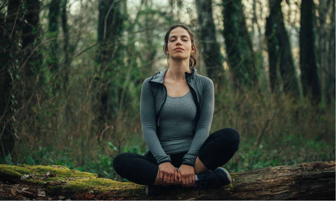 woman meditating in forest: Get grounded; How a simple practice can release anxiety and improve focus