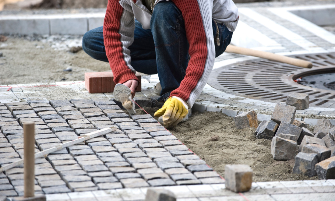 A tradesperson lays cobbles on a German street
