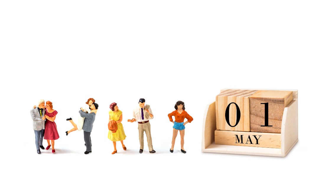 miniature dolls standing next to may 1 calendar block